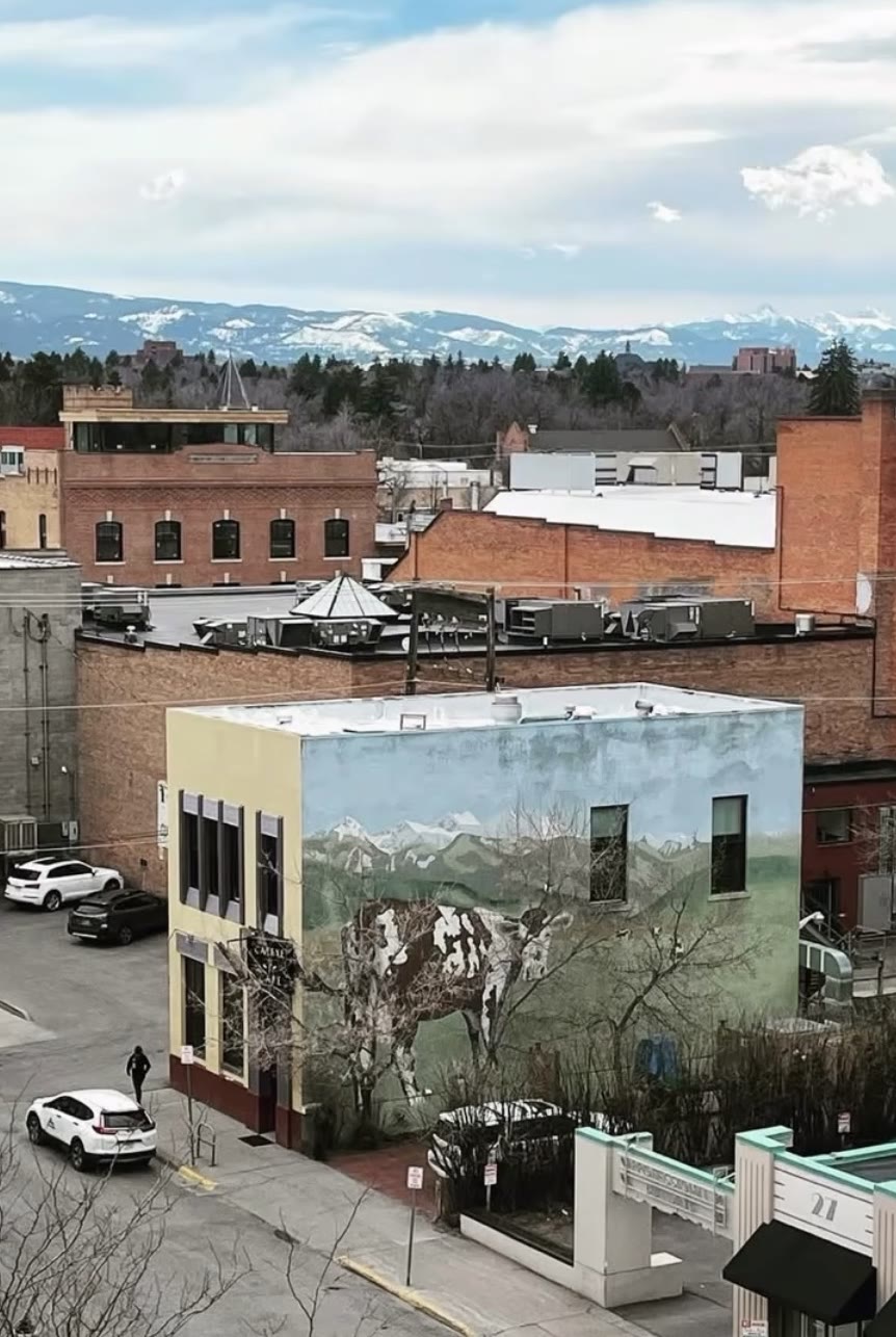 Aerial view of downtown Bozeman with the Cat Eye Café mural building and the snowy Bridger Mountains behind it